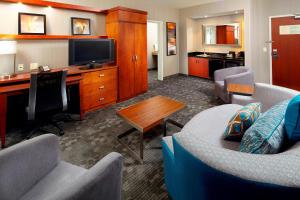 a living room with a couch and a desk with a television at Courtyard Pittsburgh Greensburg in Greensburg