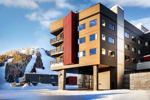 a building in the snow with a mountain in the background at The Josie Hotel, Autograph Collection in Rossland