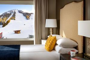 a bedroom with a bed and a window with a snow covered mountain at The Josie Hotel, Autograph Collection in Rossland