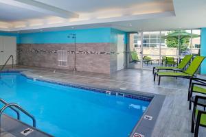 a swimming pool with chairs and tables in a building at SpringHill Suites by Marriott Grand Rapids West in Grandville