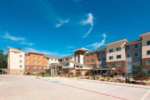 an image of an apartment complex with a parking lot at Residence Inn by Marriott Houston City Place in Spring