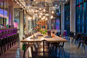 a restaurant with a large wooden table and chairs at Moxy Stuttgart Airport/Messe in Leinfelden-Echterdingen