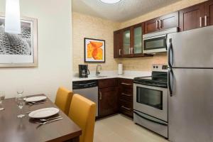 uma cozinha com um frigorífico de aço inoxidável e uma mesa em Residence Inn by Marriott Fort Myers em Fort Myers