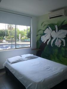 - une chambre avec un lit orné d'une peinture florale sur le mur dans l'établissement Casa de Campo Peñalisa Hotel campestre, à Ricaurte