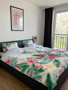 a bed with a colorful comforter on it with a window at Room in the city 2 in Sopron