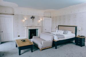 a bedroom with a bed and a chair and a table at Court Colman Manor in Bridgend