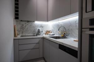 a kitchen with white cabinets and a sink at Skanderbeg Square Modern App - THE NEST in Tirana