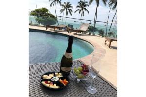a bottle of wine and a bowl of fruit next to a pool at Iracema Flat 2102 Beira Mar in Fortaleza