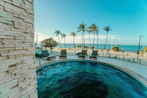 a swimming pool next to a beach with palm trees at Iracema Flat 2102 Beira Mar in Fortaleza