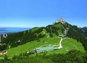 Ein grüner Hügel mit einem Gebäude darauf in der Unterkunft Sonnenalm Kampenwand in Aschau im Chiemgau