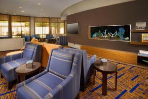 Sala de espera con sillas azules y TV de pantalla plana en Courtyard by Marriott San Antonio SeaWorld/Lackland, en San Antonio