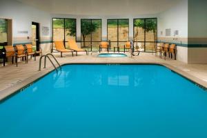 a pool in a hotel room with chairs and tables at Courtyard by Marriott San Antonio SeaWorld/Lackland in San Antonio