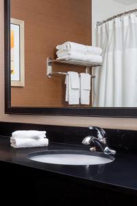 ein Badezimmer mit einem Waschbecken, einem Spiegel und Handtüchern in der Unterkunft Fairfield Inn & Suites Tyler in Tyler