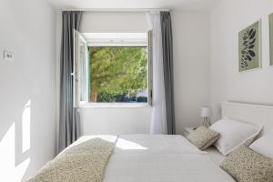 a white bedroom with a bed and a window at Cool Suite in Split