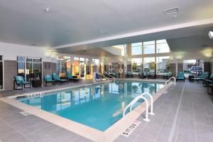 ein großer Pool in einem Hotel mit Stühlen und Tischen in der Unterkunft Residence Inn by Marriott Houston Northwest/Cypress in Cypress