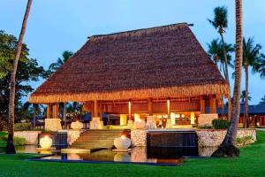 un complejo con techo de paja y palmeras en The Westin Denarau Island Resort & Spa, Fiji, en Denarau