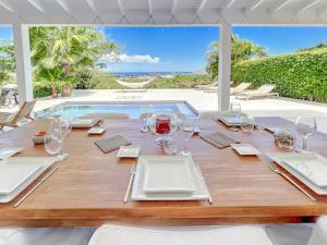 - une table en bois avec des assiettes et des verres à vin dans l'établissement Villa les Yuccas, private pool, 5 min from Grand Case, à Saint-Martin