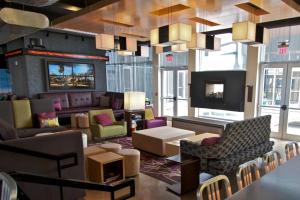 a lobby with a couch and chairs and a tv at Aloft Tulsa in Tulsa