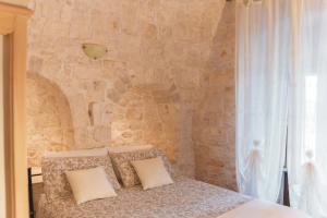 1 dormitorio con pared de piedra y 1 cama con almohadas en Masseria Montanaro, en Cisternino