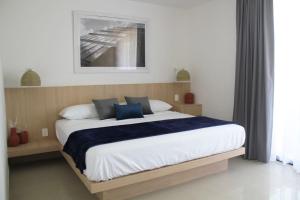 a bedroom with a large bed with blue pillows at Expo Satelite Hotel & Suites in Guadalajara