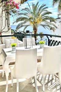 a white table and chairs on a balcony with a palm tree at MI CAPRICHO 4C BEACHFRONT -Apartment with sea view - Costa del Sol in Sitio de Calahonda