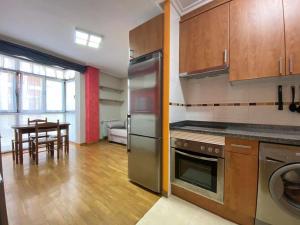 cocina con electrodomésticos de acero inoxidable y mesa en La Magdalena acogedor apartamento en Villaviciosa, en Villaviciosa