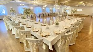 une grande salle de banquet avec des tables et des chaises blanches dans l'établissement Chata Karczowiska, à Karczowiska