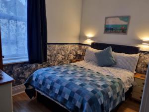 a bedroom with a bed with a blue plaid blanket at Sirocco Blues Guest House in Blackpool