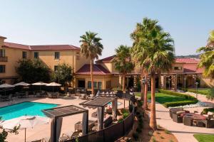 a resort pool with tables and chairs and palm trees at SpringHill Suites Napa Valley in Napa