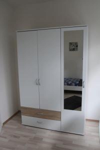 a white cabinet with a mirror in a room at Gästewohnung Pakulies in Weinheim