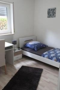 a bedroom with a bed and a desk and a window at Gästewohnung Pakulies in Weinheim
