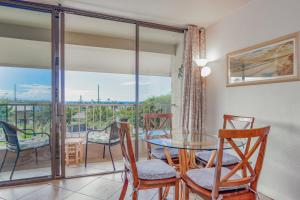 a dining room with a table and chairs and a balcony at Kalanikai 321 in Kailua-Kona