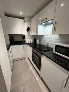 a kitchen with white cabinets and black counter tops at Luxe City Hot Tub: Urban Retreat in Norwich