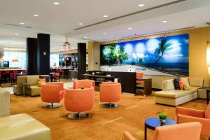 um átrio do hotel com cadeiras laranja e um grande mural em Courtyard by Marriott Miami Homestead em Homestead