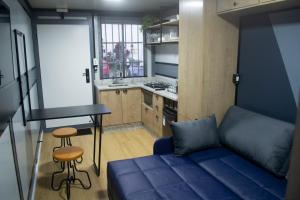 a living room with a blue couch and a kitchen at Tiny House Urban in Balneário Camboriú