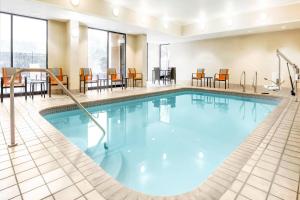 uma piscina num quarto de hotel com cadeiras e mesas em Courtyard by Marriott San Antonio Airport/North Star Mall em San Antonio