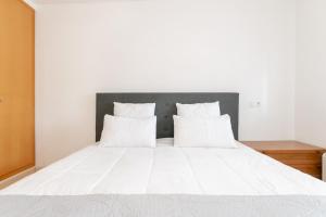 Cama blanca con sábanas y almohadas blancas en Apartamento con vista piscina, en Roses
