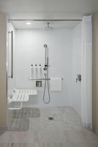 biała łazienka z prysznicem i umywalką w obiekcie Delta Hotels Calgary Airport In-Terminal w mieście Calgary