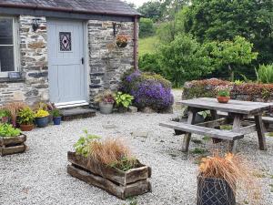 a picnic table in front of a building with plants at Mimi's Cottage in Liskeard +7 photos
