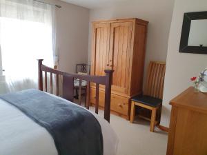 a bedroom with a bed and a wooden cabinet at Mimi's Cottage in Liskeard