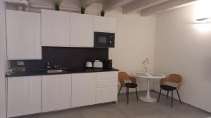a kitchen with white cabinets and a table with chairs at Room 28 in Ferrara