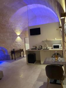a kitchen with a purple lighting in a stone building at Lo scorcio sul Barisano in Matera