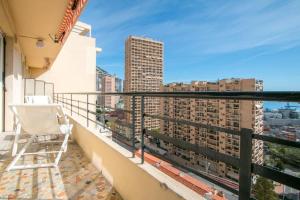 a chair on a balcony with a view of a city at Spacieux 3 Pièces de standing au centre de Monaco in Monte Carlo