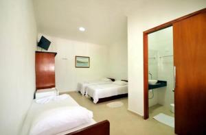 1 dormitorio con 2 camas y baño con espejo. en Pousada do Itaguá en Ubatuba