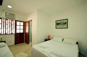 1 dormitorio con 2 camas blancas y ventana en Pousada do Itaguá en Ubatuba
