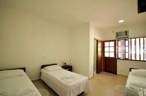 um quarto com 2 camas e uma janela em Pousada do Itaguá em Ubatuba