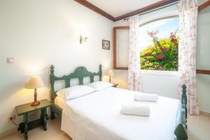 1 dormitorio con cama blanca y ventana en La Belle Villa, en Akrotiri