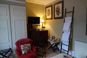 a living room with a red chair and a tv at Loch Gorm House in Bruichladdich