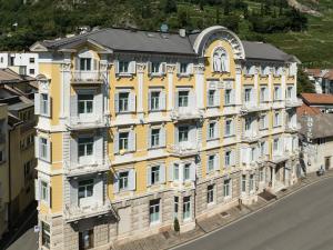 duży żółty budynek z czarnym dachem w obiekcie Hotel Stiegl Scala w mieście Bolzano