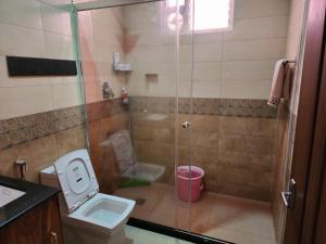 een badkamer met een douche, een toilet en een wastafel bij VanaJyotsna Forest Home in Maraiyūr